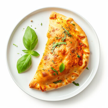 Top view of a delicious calzone pizza with fresh basil and spices on a white plate