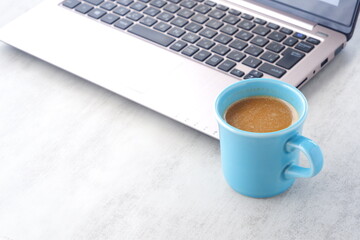 オフィスでデスクワークの合間に、牛乳をたっぷり入れたコーヒーのカフェ・ラッテを飲む
