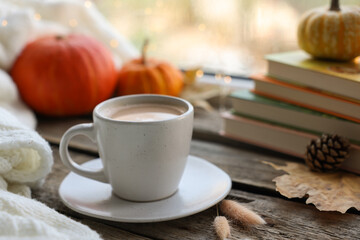 Cup of coffee, books and autumn decor on wooden table, closeup