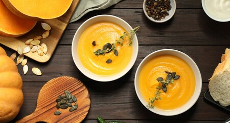 Delicious pumpkin soup served on wooden table, flat lay