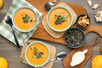 Delicious pumpkin soup served on wooden table, flat lay