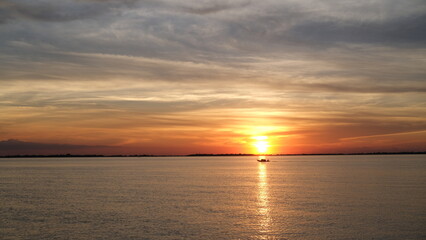 sunset over the river, a boatman's silhouette is seen riding his boat.