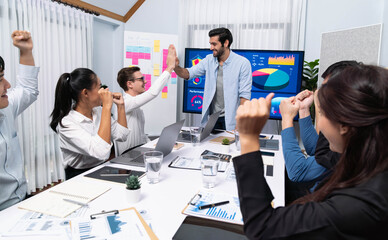 Analyst team leader celebrate and high five together with his colleague after successful data analysis meeting using FIntech software power with business intelligence or BI dashboard. Prudent