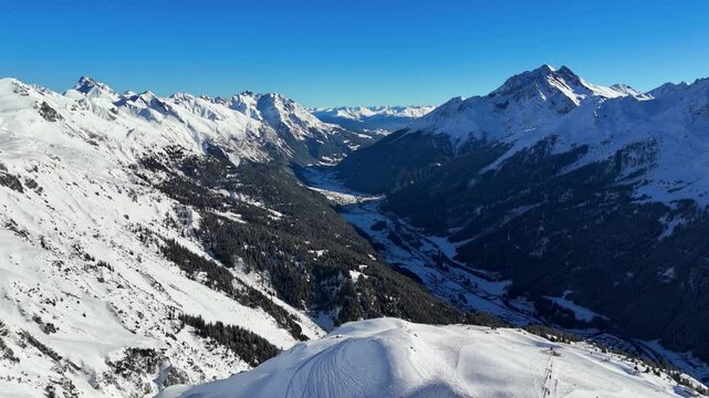 St Anton am Arlberg, Austria: Aerial view of famous ski resort, breathtaking winter panorama of snow-covered Alpine mountains, sunny day with clear blue sky - landscape panorama of Europe from above
