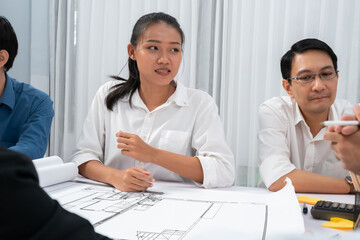 Fototapeta premium Diverse group of civil engineer and client working together on architectural project, reviewing construction plan and building blueprint at meeting table. Prudent
