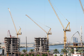 residential buildings under construction with cranes at construction site