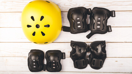 roller skates and body parts protection on white table. top view of inline rollers, helmet, knee...