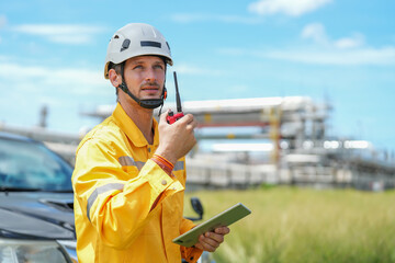 Obraz premium portrait refinery worker wears safety and harthat using walkie talkie to communicate with team while inspecting oil refinery industry