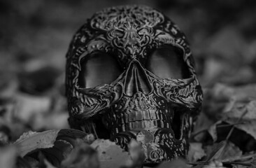 Halloween decor, plastic skull with Mexican Day of the Dead pattern among yellow autumn leaves....