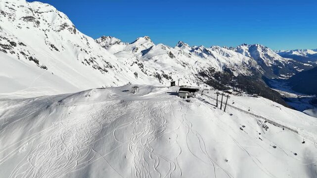 St Anton am Arlberg, Austria: Aerial view of famous bustling ski resort in Tyrolean Alps. Snow-covered slopes with ski runs, sunny day with clear blue sky - landscape panorama of Europe from above
