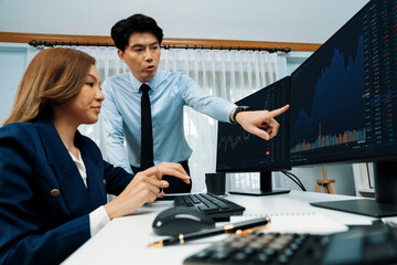 Asian business partners pointing to profit highest dynamic stock exchange data on computer screen value rate online website program. Investor showing financial on real time at modern office. Infobahn.