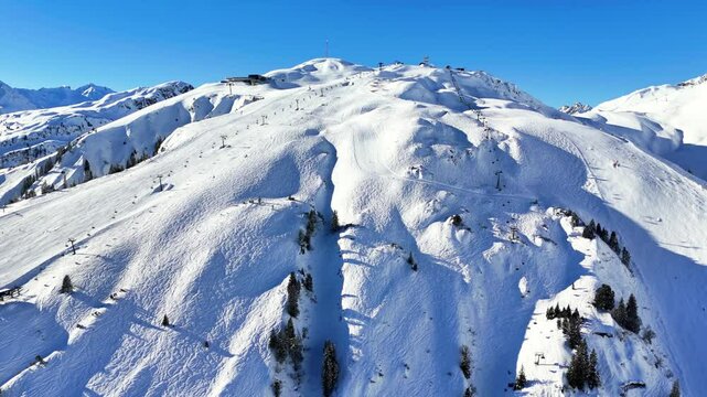 St Anton am Arlberg, Austria: Aerial view of famous bustling ski resort in Tyrolean Alps. Snow-covered slopes with ski runs, sunny day with clear blue sky - landscape panorama of Europe from above
