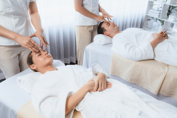 Obraz premium Caucasian couple enjoying relaxing anti-stress head massage and pampering facial beauty skin recreation leisure in dayspa modern light ambient at luxury resort or hotel spa salon. Quiescent