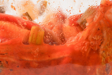 The process of making homemade kimchi using a tightly sealed glass jar. Kimchi is a traditional Korean side dish (banchan) consisting of salted and fermented vegetables. Isolated on white background.
