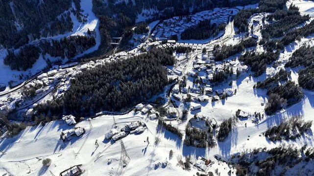 St Anton am Arlberg, Austria, Europe: Aerial view of ski resort in snowy Tyrolean Alps. Charming village landscape with chalets and hotels surrounded by snow-capped peaks, sunny day, clear blue sky
