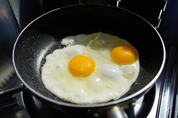 Fried eggs in a frying pan on a gas stove in the kitchen
