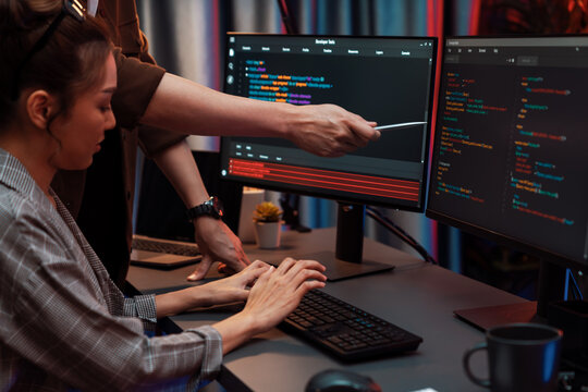 IT developers discussing with point to intelligent website development coder system running data online two screens information technology at neon light room at modern office. Infobahn.