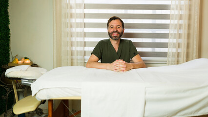 Obraz premium Happy male therapist in a massage room, radiating confidence and joy