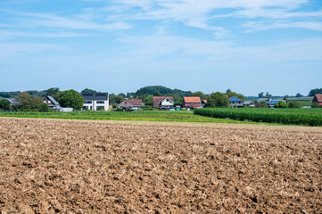 Plowed agriculture fields and houses at the Flemish countryside in Bekkevoort, Flemish Brabant, Belgium