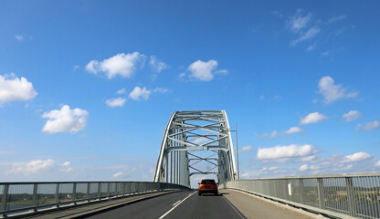 Fototapeta premium road with a large metal truss bridge and a car crossing it