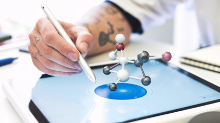 A close-up of a chemist's hand using a stylus to manipulate a virtual 3D model of a molecule on a touchscreen, demonstrating molecular interaction analysis.