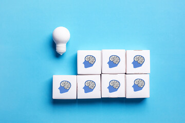 Lightbulb and stacked head brain boxes against a bright blue background. This abstract composition represents innovation