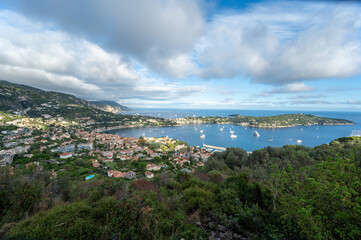 Yachts at anchor in natural harbor of Villefranche-sur-Mer on sunny summer afternoon.