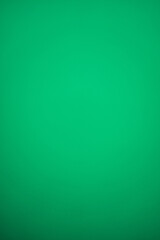 Vertical plain green background with a slight gradient and metallic shiny effect, darkening downwards. Blank backdrop for graphic design with copy space for Christmas, New Year or Saint Patrick's Day.