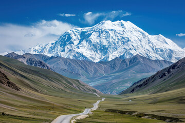 A high-altitude snow-capped mountain with a winding road cutting through the valley below