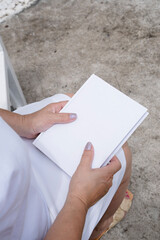 unrecognizable woman holding blank book for mockup design, sitting on bench