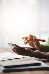 Close-up of young woman's hand working with tax and accounting documents using laptop and...