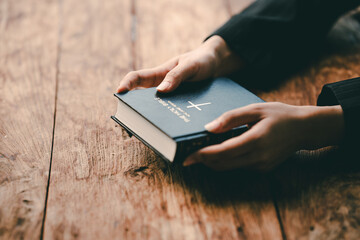 Cropped view of young woman praying with bible on table Confession concept Pray and talk with God