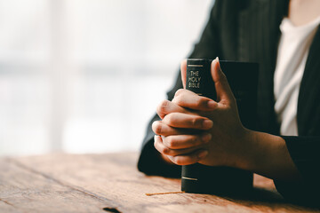 Cropped view of young woman praying with bible on table Confession concept Pray and talk with God