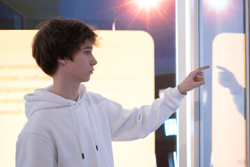 Young man using interactive touchscreen kiosk - scrolling and touching. Education, and technology...