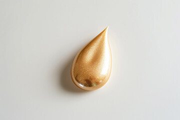 Fototapeta premium A closeup of a glossy drop of liquid highlighter in a beautiful gold shade, against a white background for a decorative and abstract look