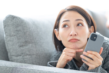 悩む女性・スマホ