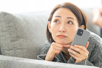 スマホを持って悩む女性