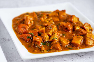 A delicious plate of spicy chicken. savory chunks of chicken immersed in a rich, flavorful sauce, dotted with herbs and spices.