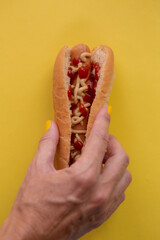 Woman's hand trying to grab a hot dog with keptchup and mustard.