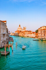 Beautiful view of traditional Gondola on famous Canal Grande with Basilica di Santa Maria della Salute in golden evening light at sunset in Venice, Italy.