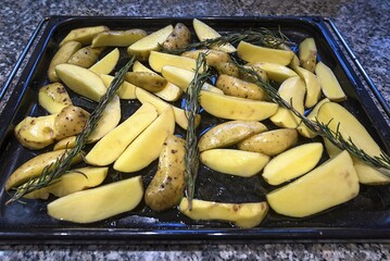 Quartered, oiled rosemary potatoes on a baking tray, Germany, Europe