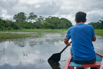 Adult fishing on traditional wooden canoe , Amazon natural reserve