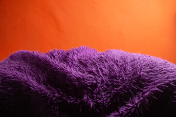 a soft purple wavy blanket with an orange wall behind it. background wallpaper for the front view of the product