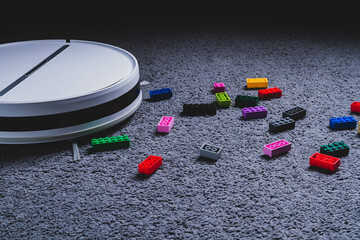 A robot vacuum cleaner cleans children's toys on the floor. Carpet and laminate cleaning. Assembling cubes with a robot vacuum cleaner.