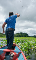 Adult fishing on traditional wooden canoe , Amazon natural reserve