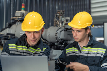 Engineer standing by robotic arm and operating machine in industry factory, technician worker check for repair maintenance electronic operation