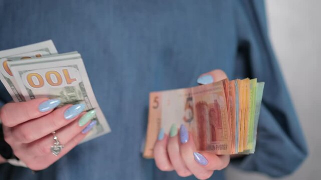 Female hands holding paper bills of US dollars and Belarusian rubles