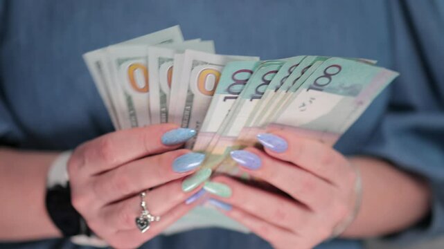 Female hands holding paper bills of US dollars and Belarusian rubles
