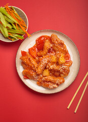 Delicious sweet and sour stir fry chicken kung pao with sesame seeds, colorful veggies, and chopsticks on a plate. Classic dish of China