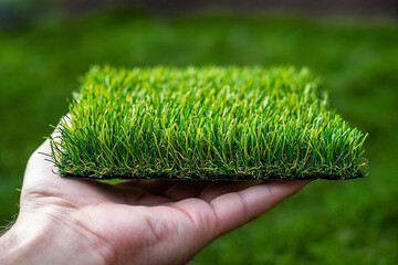 Artificial grass sample. Persons hand holding artificial grass sample. Hand holding a piece of artificial grass. Synthetic grass sample. Artificial turf sample.